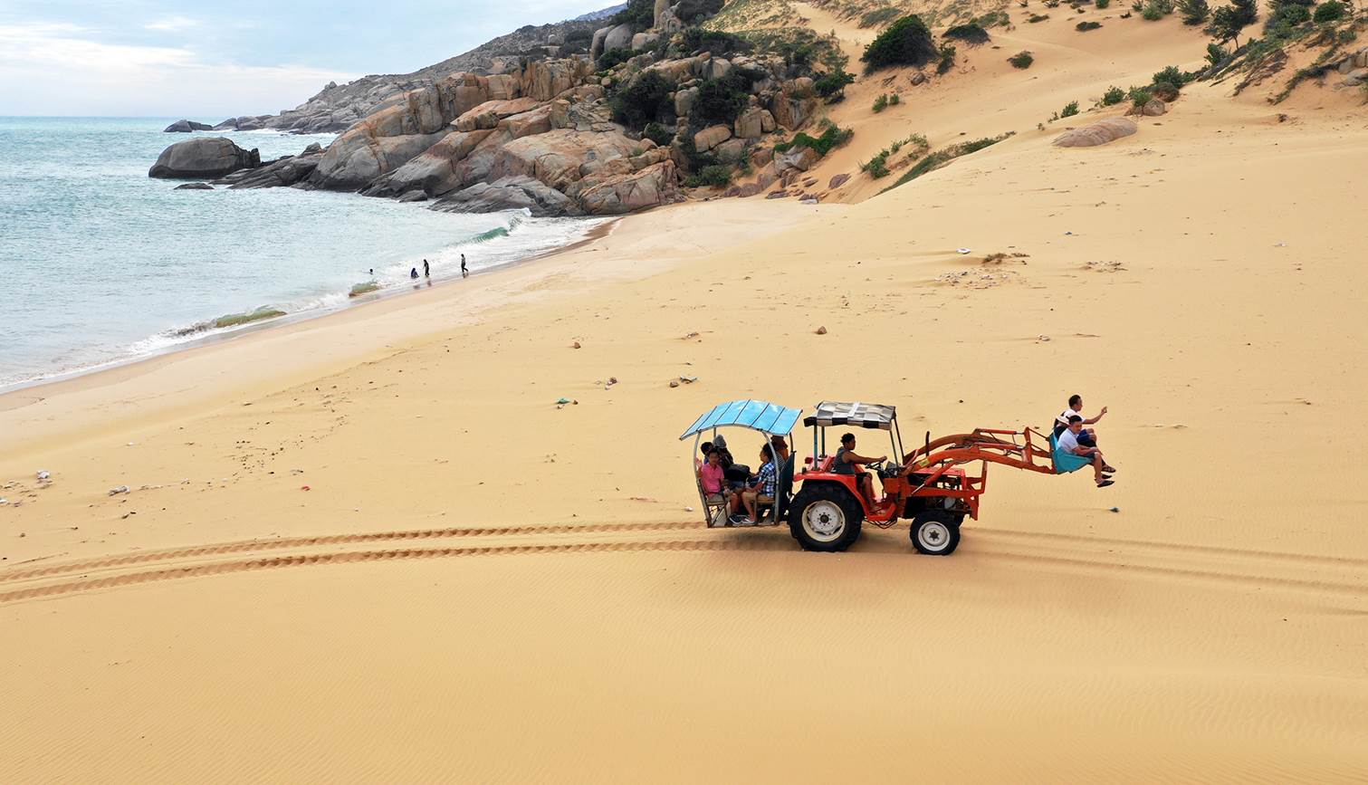 Xe xúc chở khách vượt đồi cát